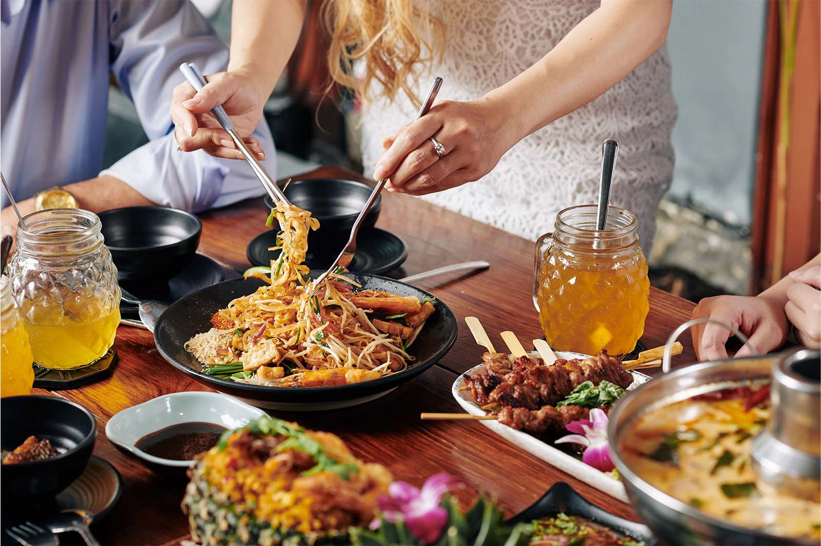 Evergreen Thai group dinner table with shared noodles skewers drinks and soup in a downtown Toronto setting